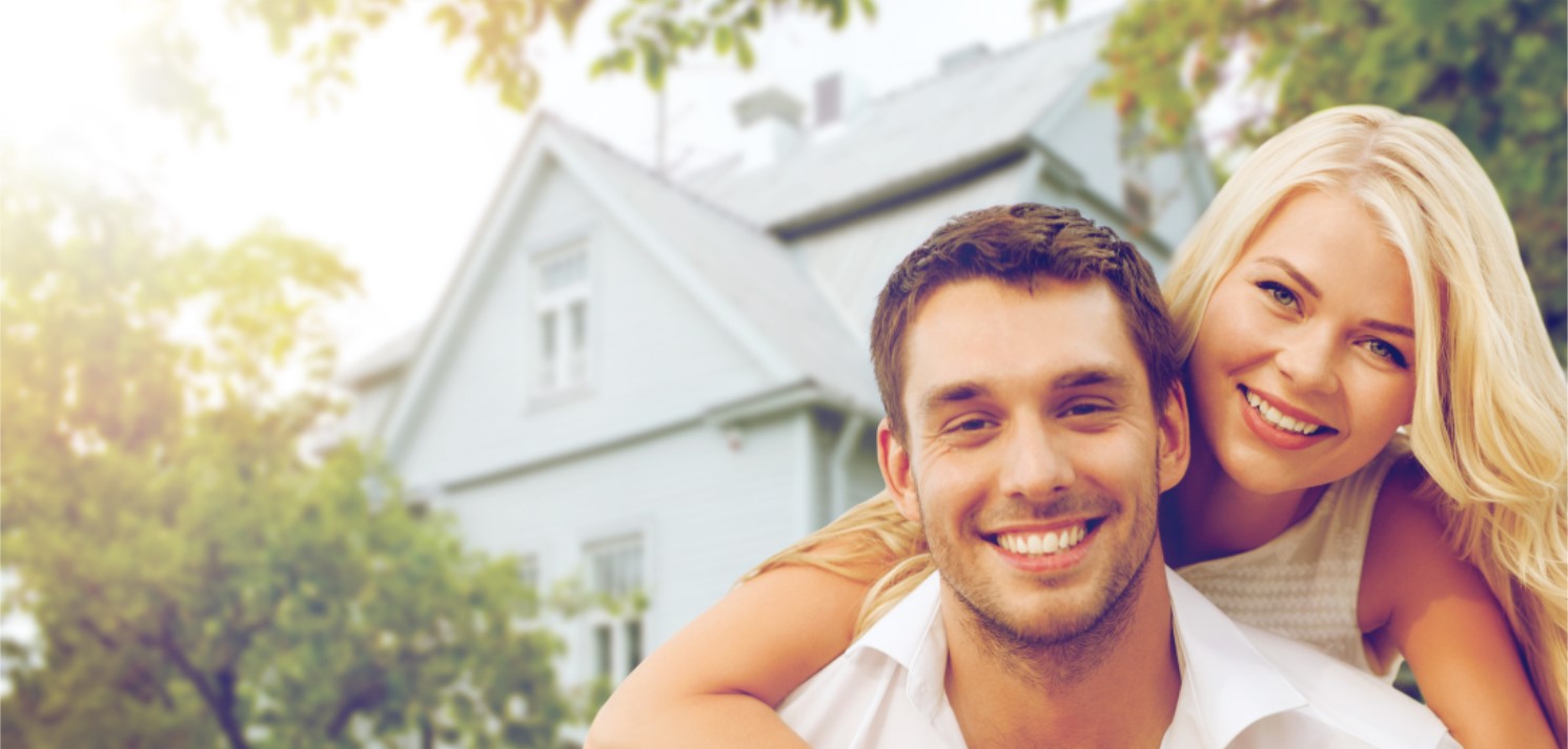 young couple standing in front of house